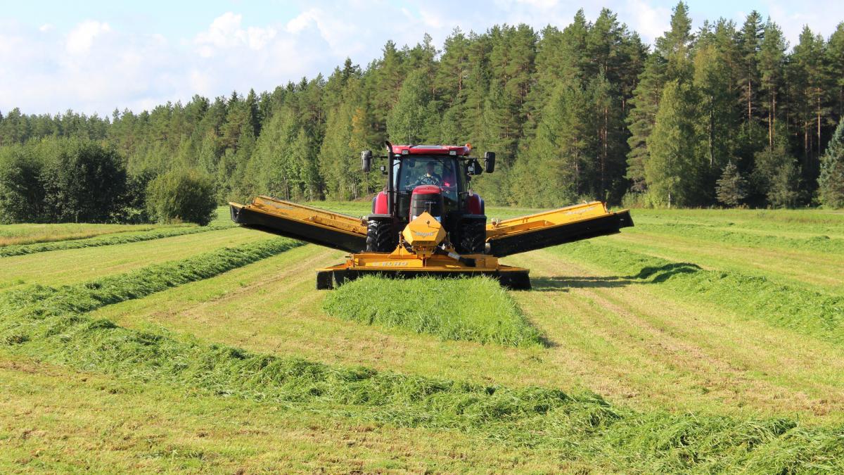 Tractor with mower attachments at work in a field